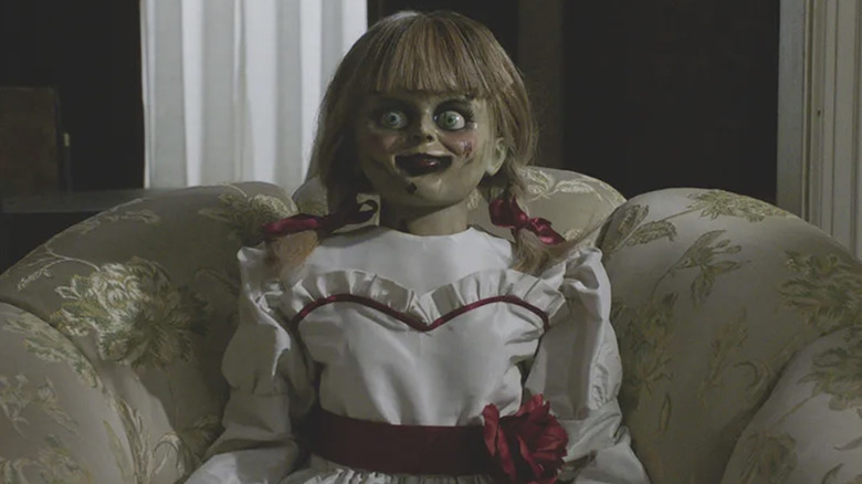 The Annabelle doll posed on a couch