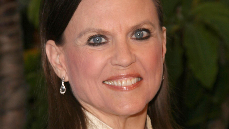 Ann Reinking smiling at event with green background