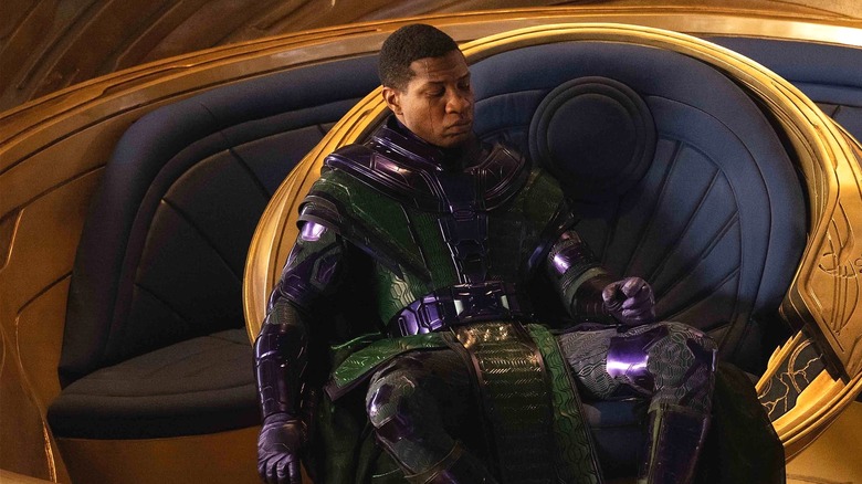 Kang sits on his throne and looks down at his hand