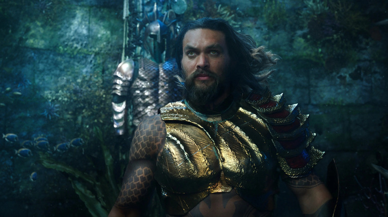 Aquaman standing in front of a suit of armor