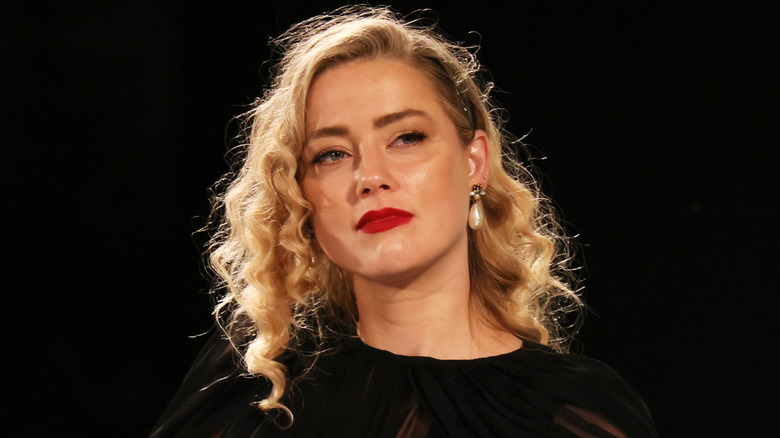 Amber Heard in black dress in front of black background