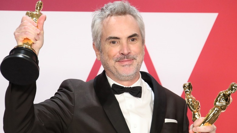 Alfonso Cuarón holding three Oscars
