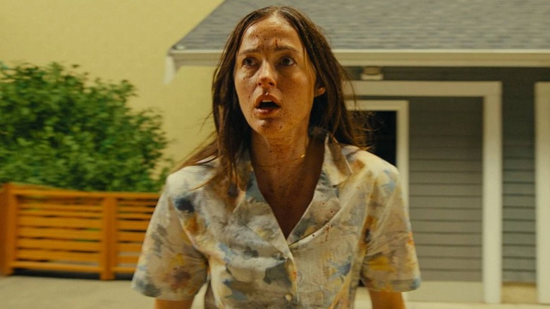 Mary looking shocked in front of a house in Backrooms