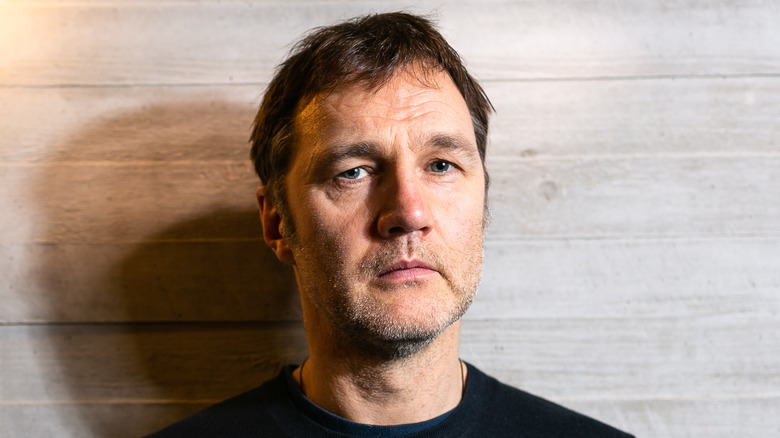 David Morrissey with wood panel wall
