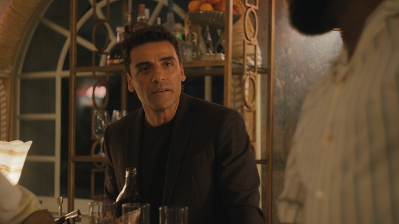 Josh seated at a table, holding a bottle, in "Beef."