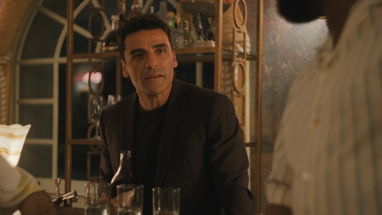 Josh seated at a table, holding a bottle, in "Beef."