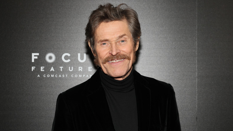 Willem Dafoe with mustache smiling