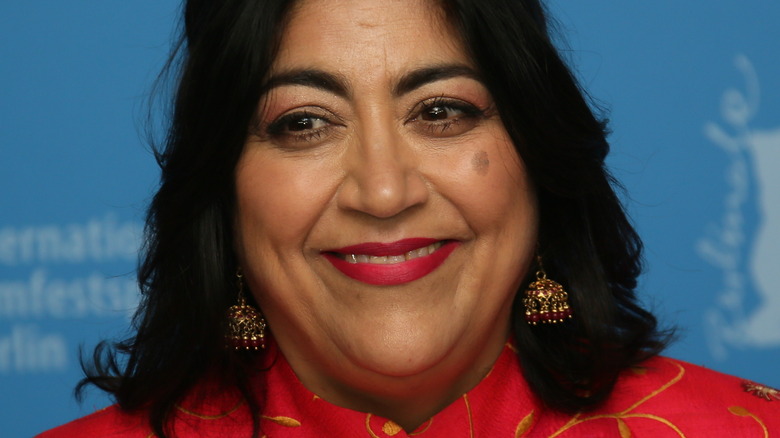 Gurinder Chadha smiling on red carpet 