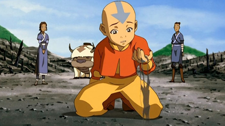 Aang kneeling with Katara, Sokka, and Appa in the background in Avatar: The Last Airbender