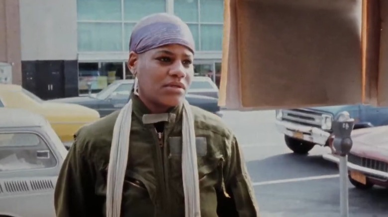 Honey looking at a sign on the street in Born in Flames (1983)