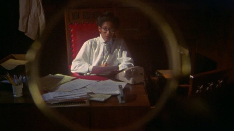 Sara Rogers sitting at her desk seen through a monocle in Losing Ground (1982)