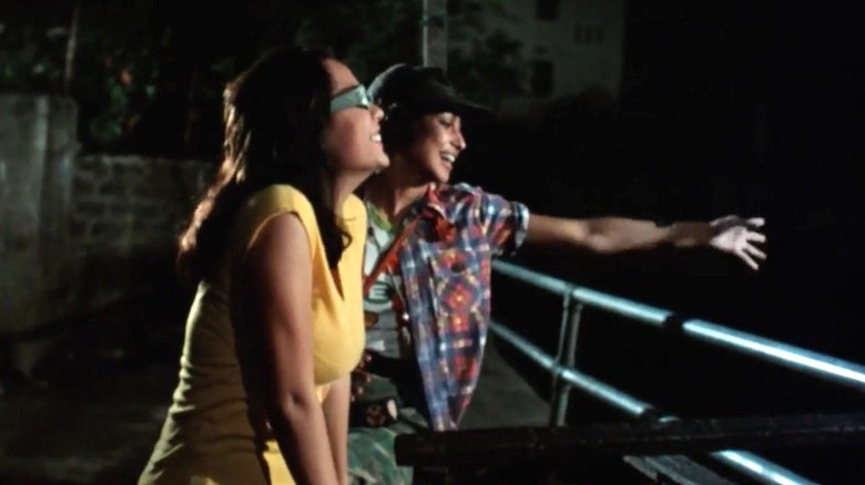 Bea and Kano laughing by a river railing in Manila by Night (1980)