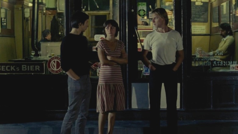 Woman standing between two men in Toute une Nuit (1982)