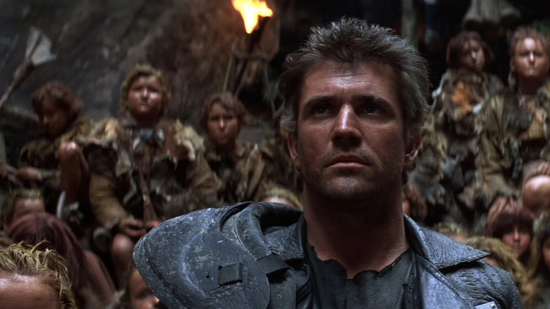Mad Max stands in front of a group of children