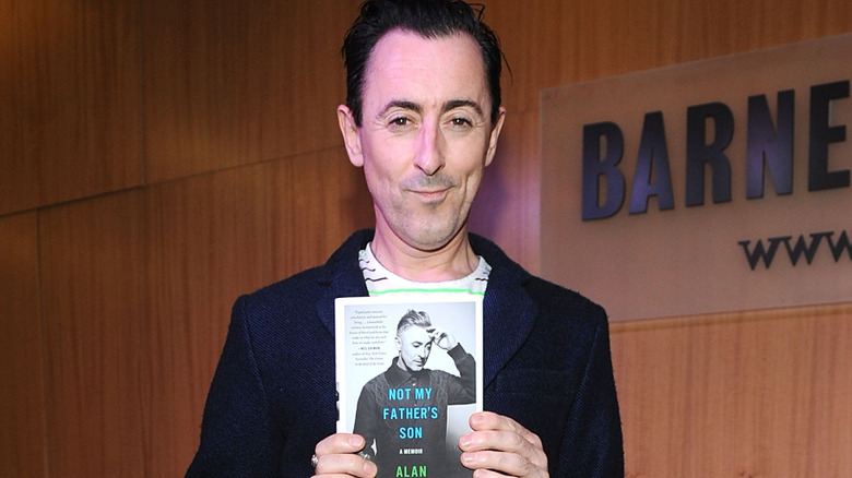 Alan Cumming holding a book