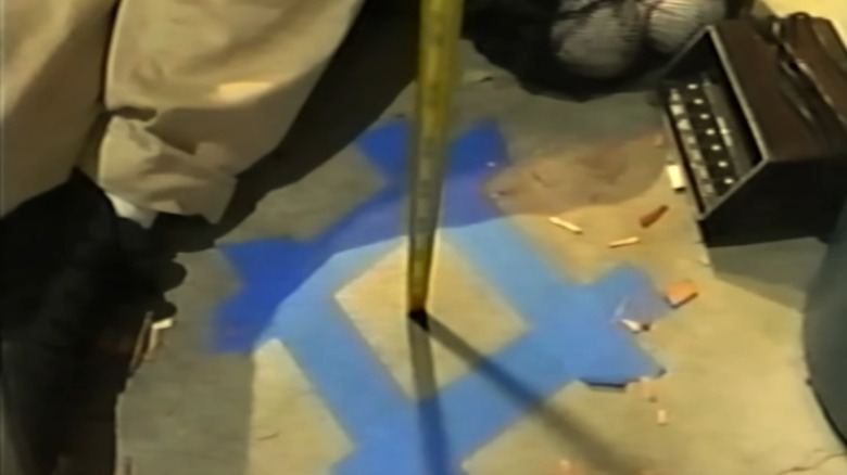 A girl putting measuring tape into an open space in the floor in The Backrooms
