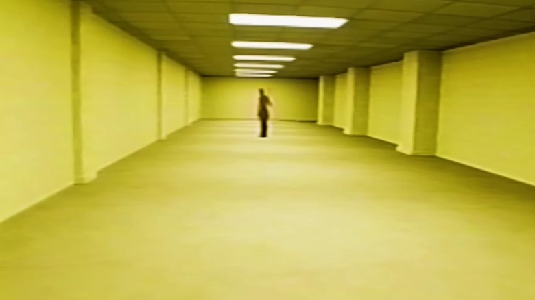 A figure standing in the middle of the hallway in The Backrooms