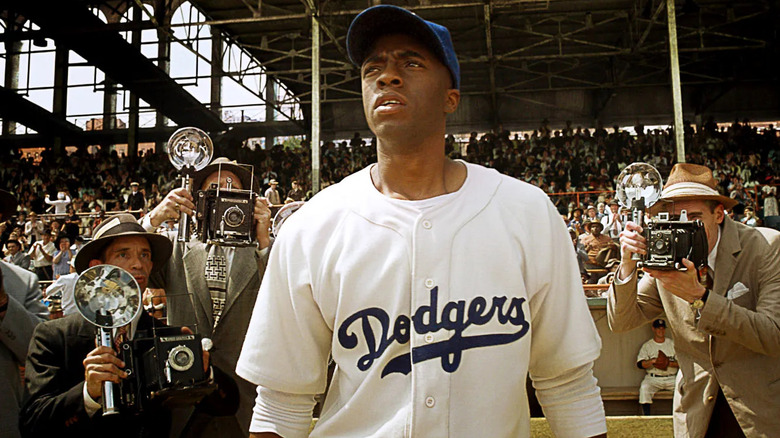 Pro-baseball player Jackie Robinson watching the field with photographers in the background