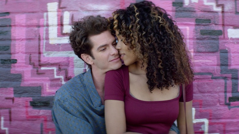 Jonathan sitting against a magenta and black wall with his girlfriend, Susan, on his lap