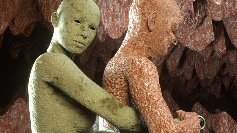 Two stone figures embrace in a cave in Kuso