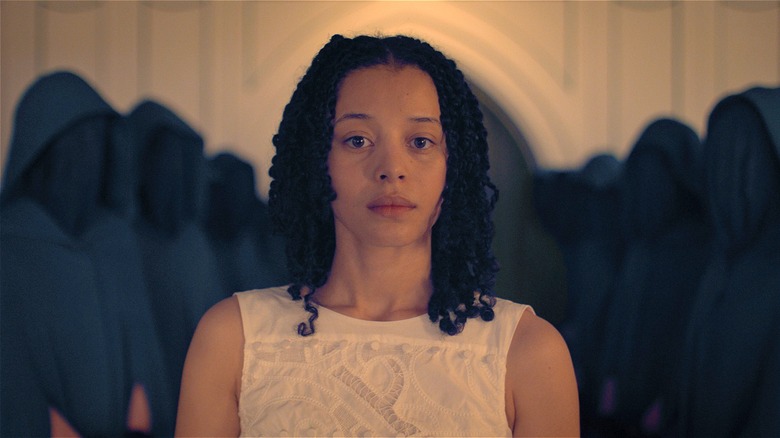 Agnes stands with hooded figures behind her in The Testaments