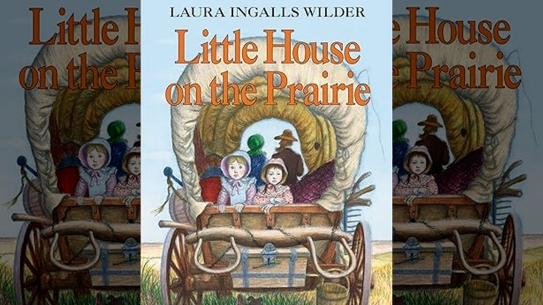 A family rides in a covered wagon on the book cover of Little House on the Prairie