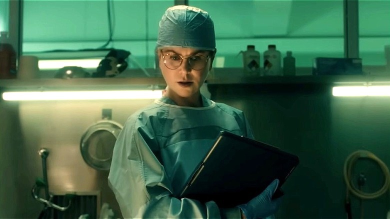 Dr. Kay Scarpetta stands in scrubs in her examination room in Scarpetta