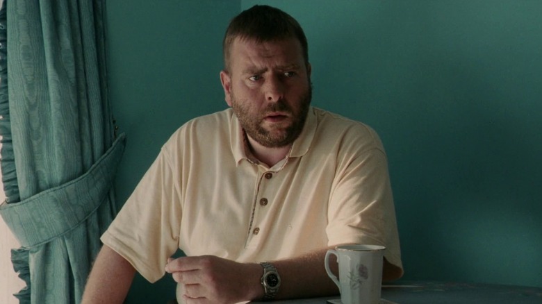 Maurice sitting at a table with a porcelain cup in front of him in Secrets & Lies