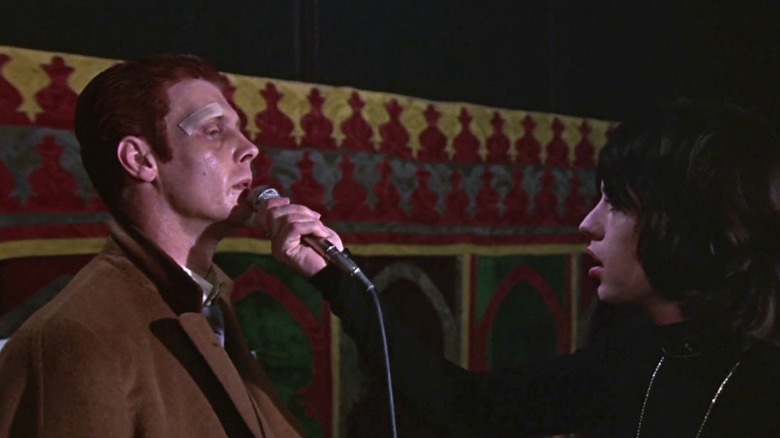 Turner holding a microphone to Chas' mouth in Performance