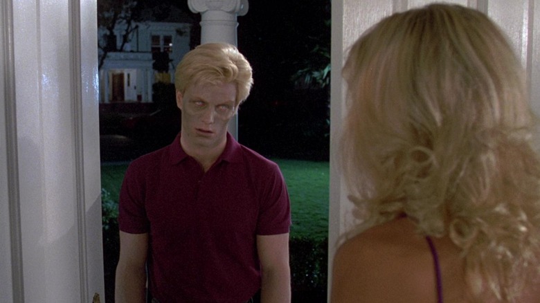 A blond zombie stands in a doorway