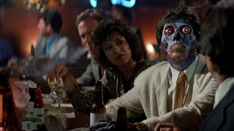 An exposed alien watching a TV broadcast at a bar in "They Live"
