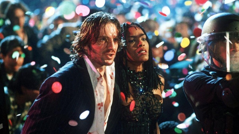 Lenny Nero and Mace walk through a New Years Eve celebration in "Strange Days" (1995)