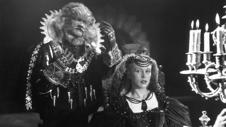 The Beast stands behind Belle sitting by candles in "Beauty and the Beast" (1946)