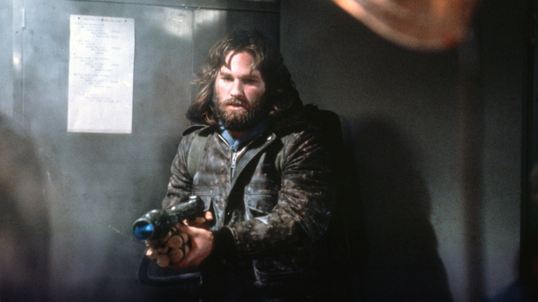 Kurt Russell aiming a flamethrower