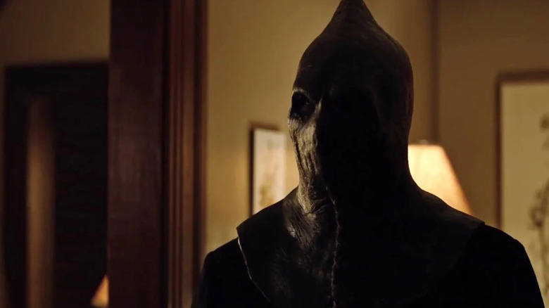 The Executioner standing in a house, wearing his hood in "Slasher" (2016-2023)