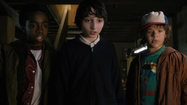 Young Lucas, Mike, and Dustin staring down at something in "Stranger Things" (2016-2015)