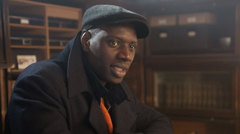 Assane speaking while sitting and looking to his right on Lupin