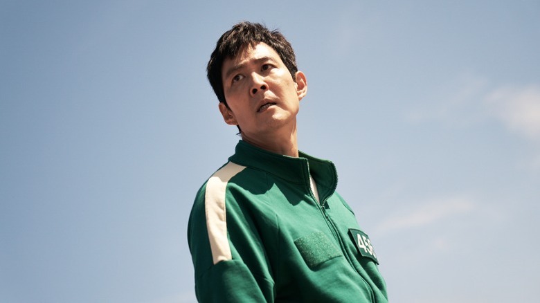 Gi-hun standing in player uniform under the open sky on Squid Game