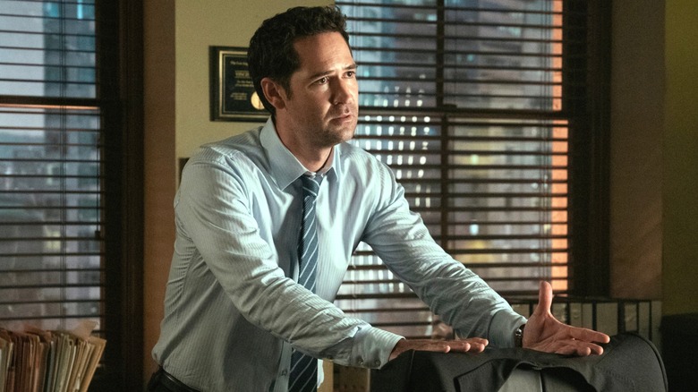 Mickey Haller frowning with his hands on the back of a chair in 