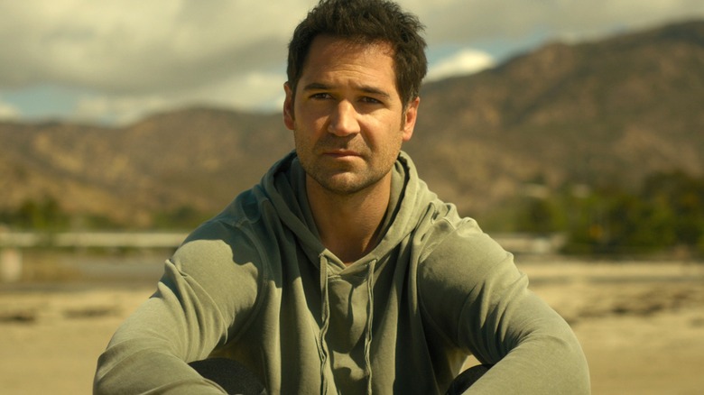 Mickey Haller frowning and sitting on the ground in "The Lincoln Lawyer."