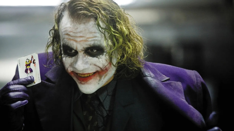 The Joker holding up a playing card in The Dark Knight