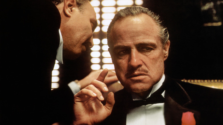 Bonasera whispering in Don Vito Corleone's ear in 