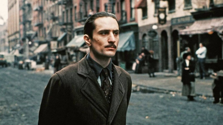 A young Vito Corleone walks down the streets of 1900s era New York City in a brown jacket in "The Godfather Part 2"