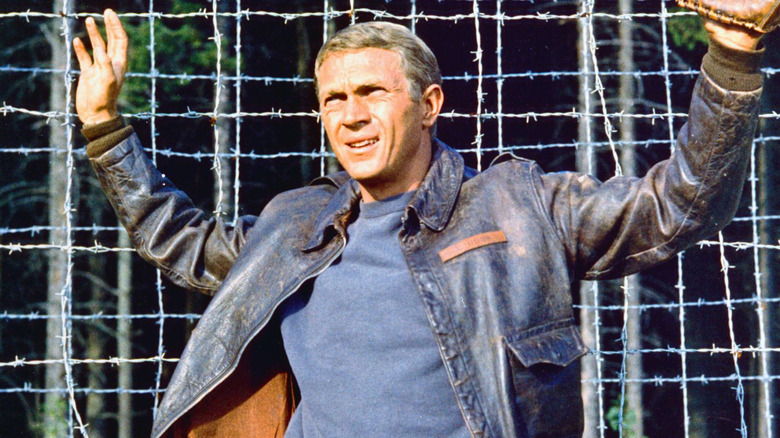 Hilts holding his hands up next to a barbed wire fence in The Great Escape (1963)