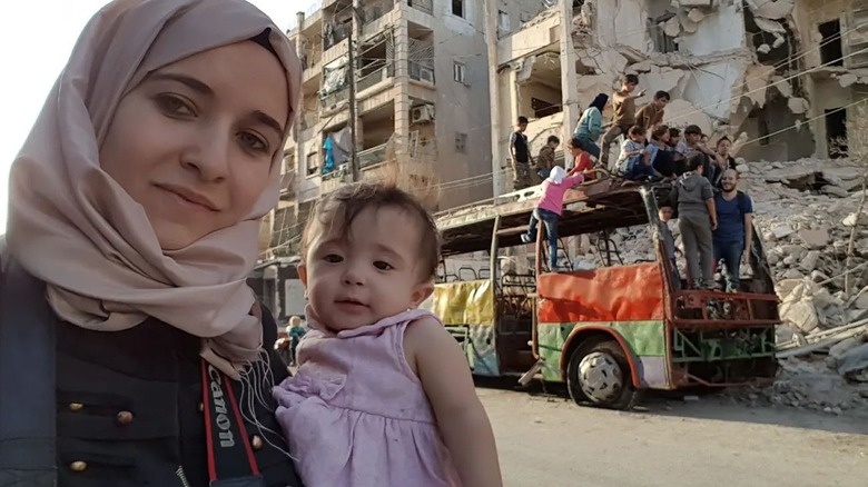 Waad Al-Kateab holding her daughter in For Sama (2019)