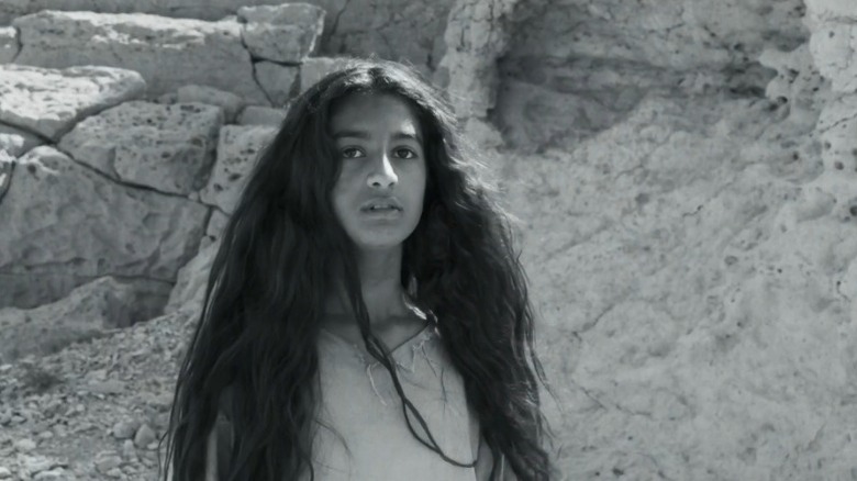 Hayat standing in front of a rock formation in Scales