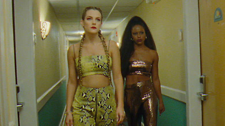 Stefani and Zola walking down hotel hallway in "Zola"