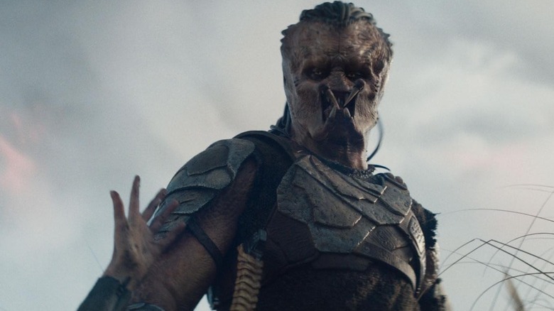 Dek looking down at a hand reaching up in "Predator: Badlands" (2025)