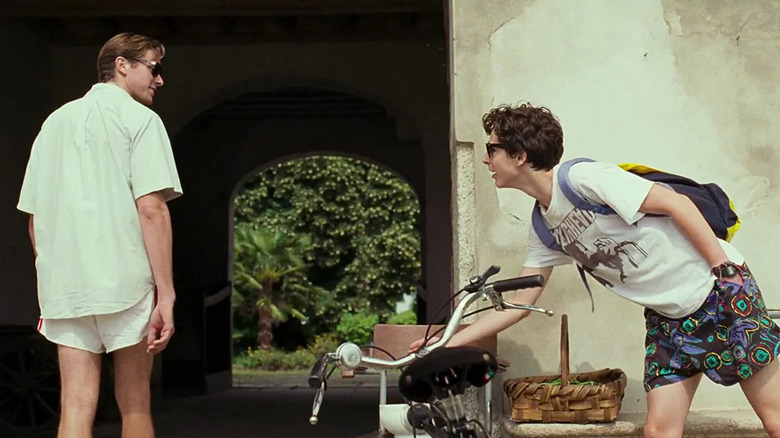 Oliver looks over his shoulder at Elio, who is parking his bike, in "Call Me By Your Name" (2017)