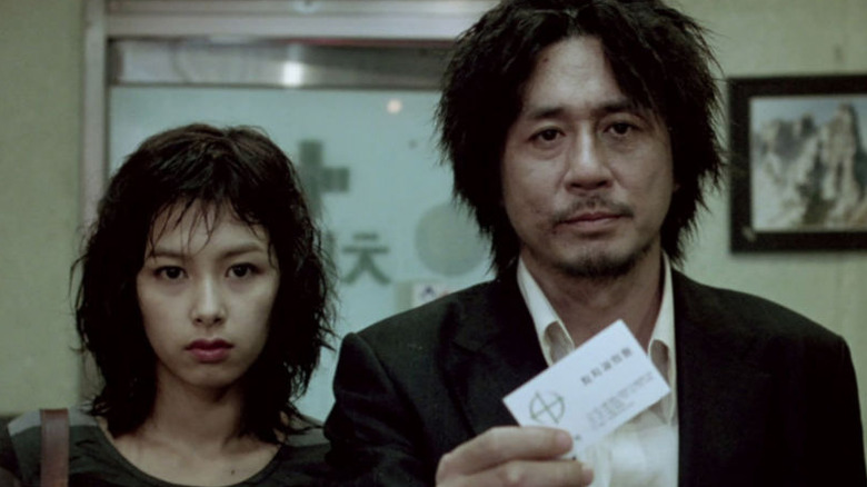 Dae-su holds a card and Mi-do looks on in "Oldboy" (2003)